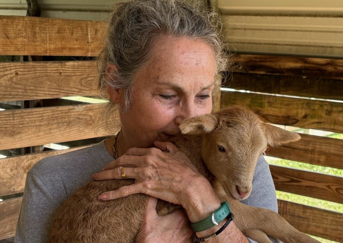 Teri holding her neighbor's newborn baby lamb